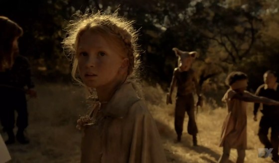 Flora staring at the camera with the Pig Man right behind her on American Horror Story: Roanoke